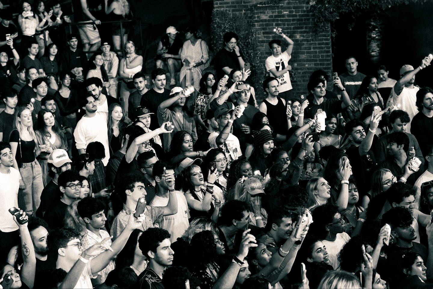 Black-and-white crowd photo from Superbloom with attendees holding up phones.
