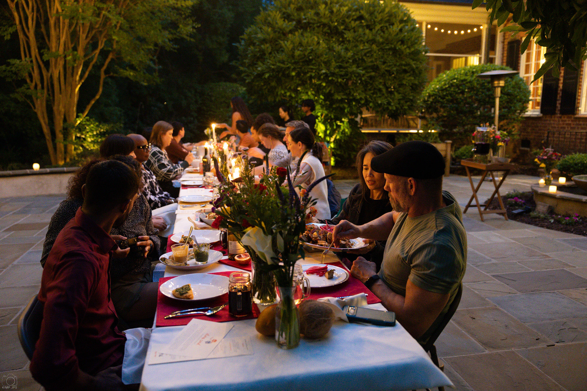 Guests seated around a long outdoor Nêm Nếm dinner table at night.